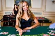 A live dealer standing behind a casino table.