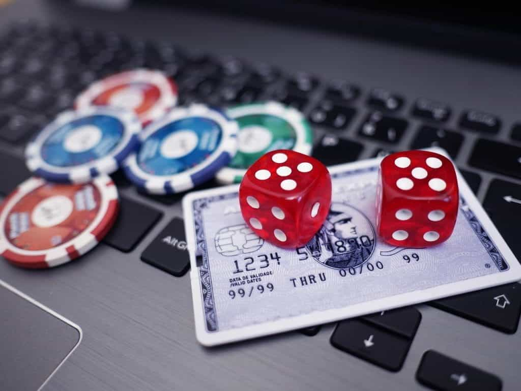 Dice, chips and a credit card on a laptop. 