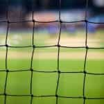 A black colored goal net on a soccer field.