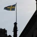 A flag hoisted at the top of a building against a blue sky.