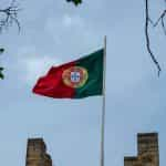 A flag hoisted on a building against the blue sky.