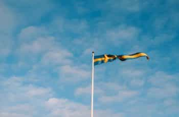 A blue and yellow flag against a blue sky.