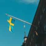 A blue and yellow flag hoisted from a building against a blue sky.